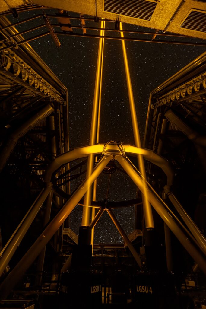A telescope silhouetted against a star-filled night sky